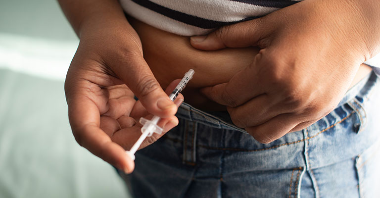 person injecting IVF medication into side