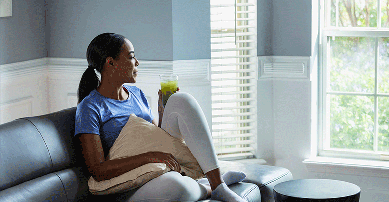 seated woman drinking healthy green juice