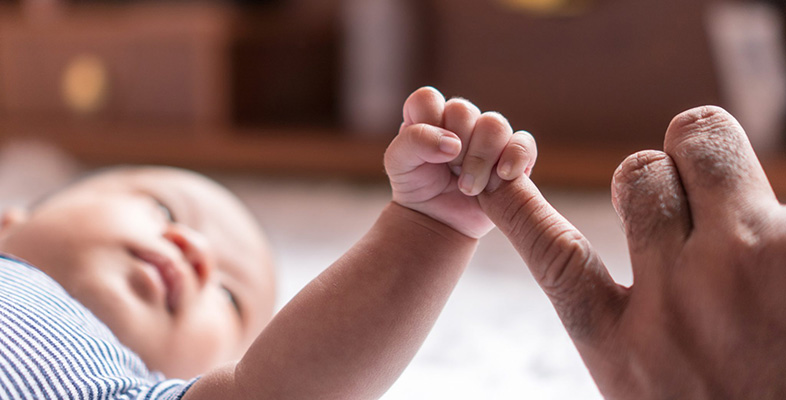 baby grasping the finger of an adult