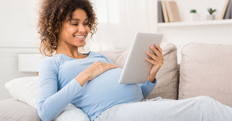 smiling pregnant woman reading on iPad