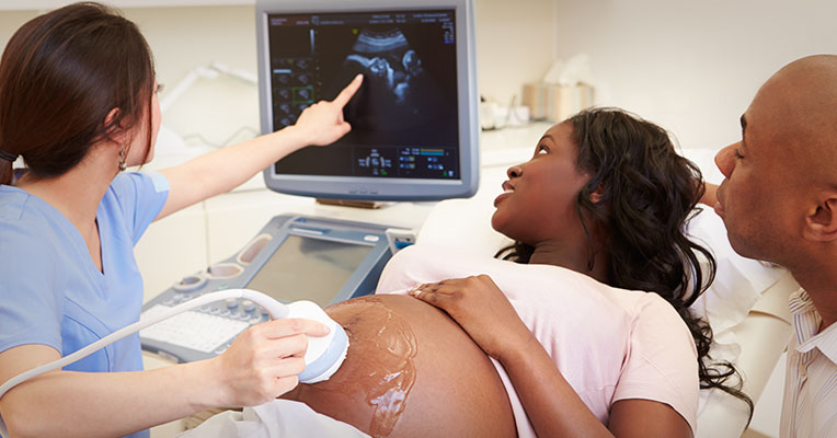 pregnant woman undergoing ultrasound with the support of her partner