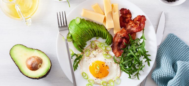 plate with avocado, bacon, eggs and greens
