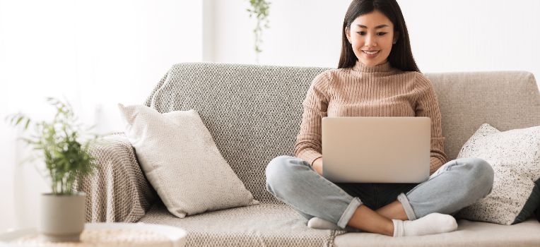 smiling woman looking at laptop on couch