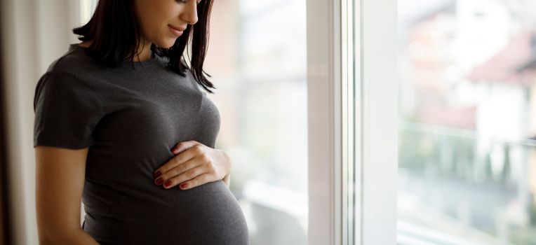pregnant woman peering at baby bump