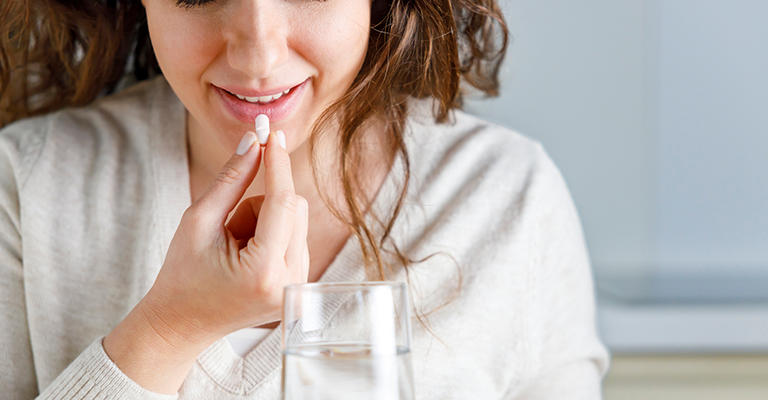 woman about to swallow a pill