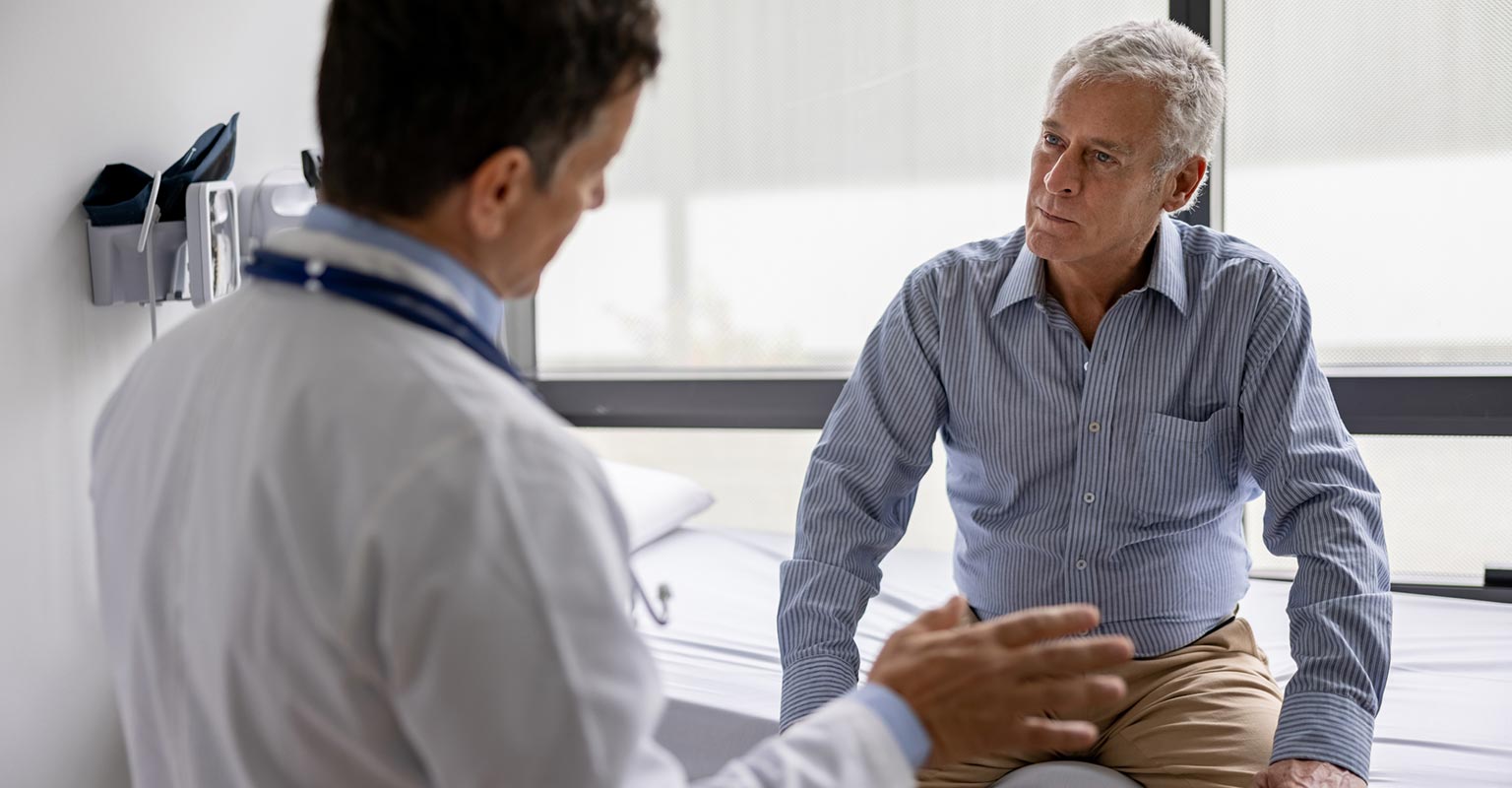 doctor consulting with seated male patient in waiting room