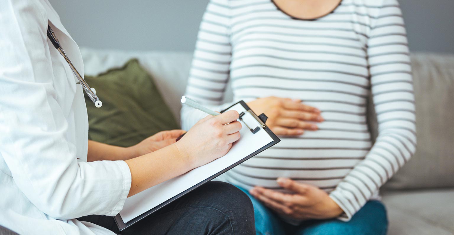 seated pregnant woman consulting with her provider