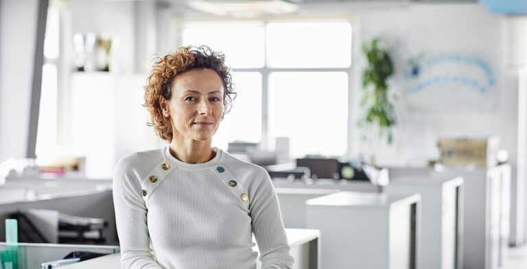 standing woman leaning against desk in the workplace