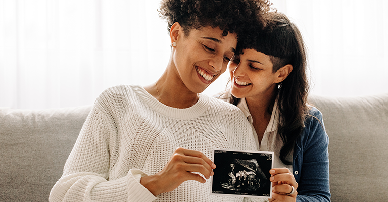 two women holding an ultrasound photo