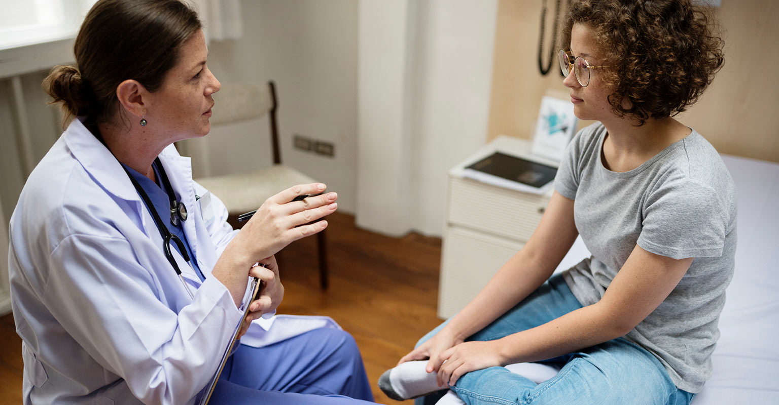 provider discussing with younger patient in exam room