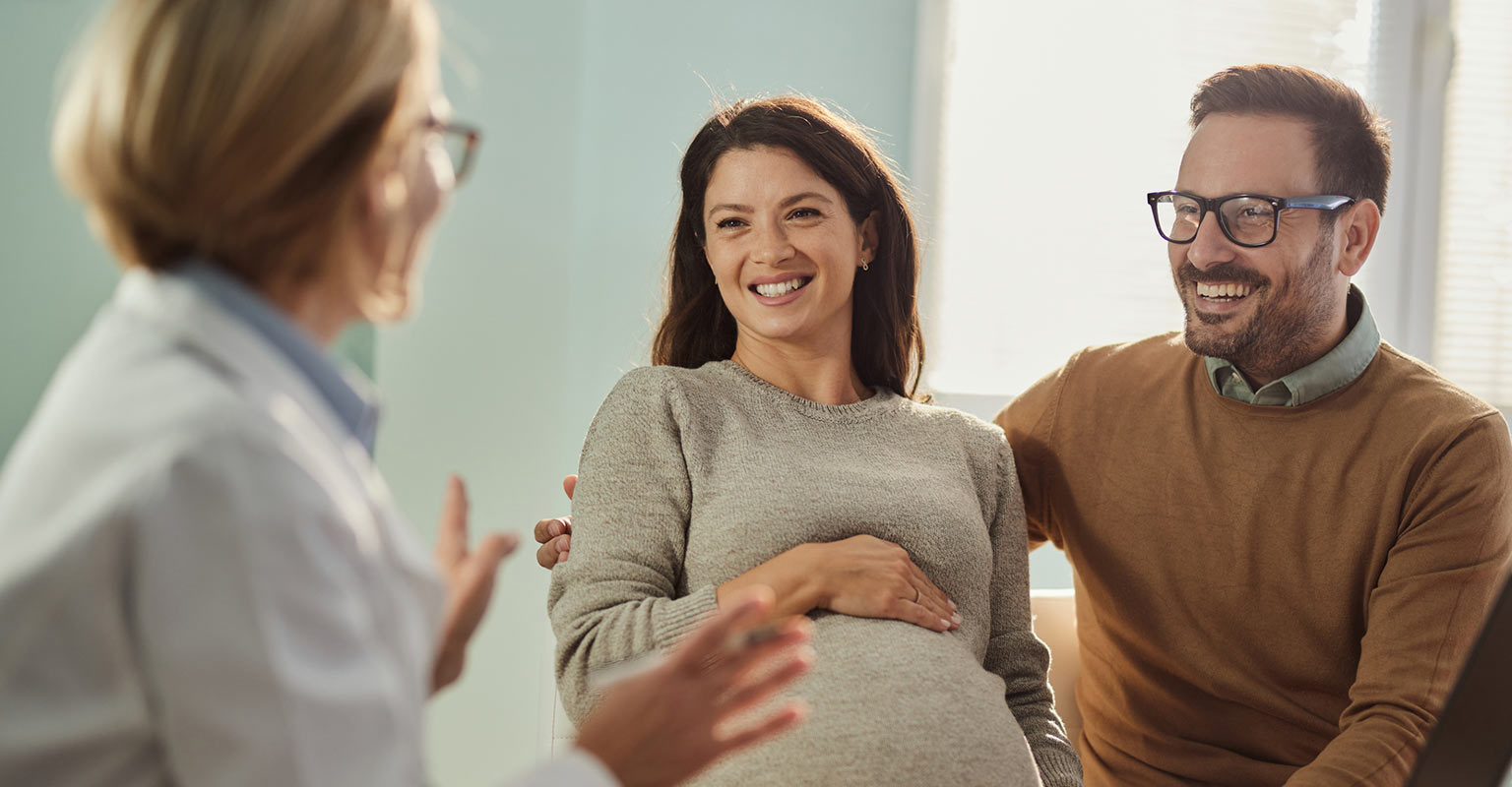 joyful pregnant couple consulting with doctor