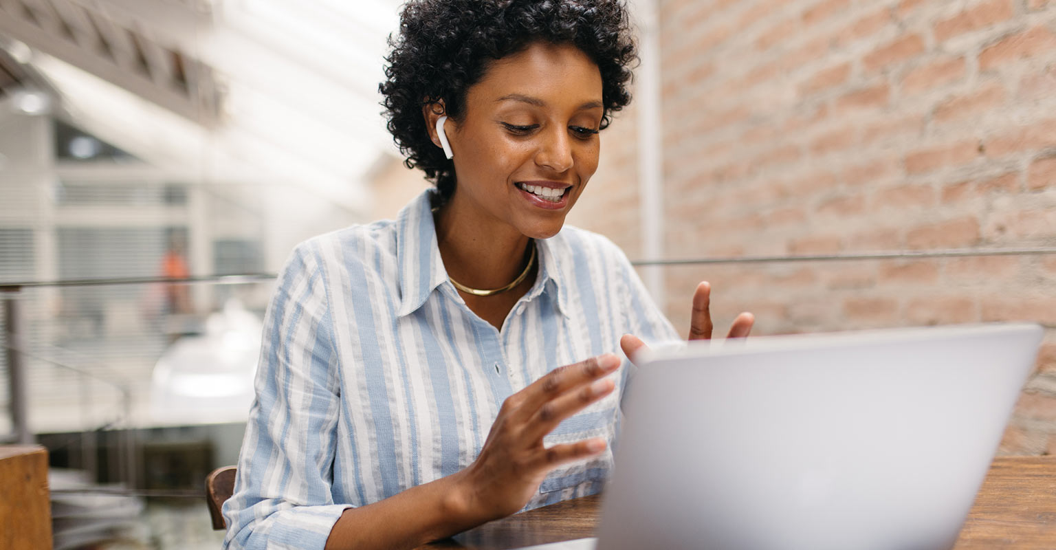 Smiling woman talking on the phone with a computer