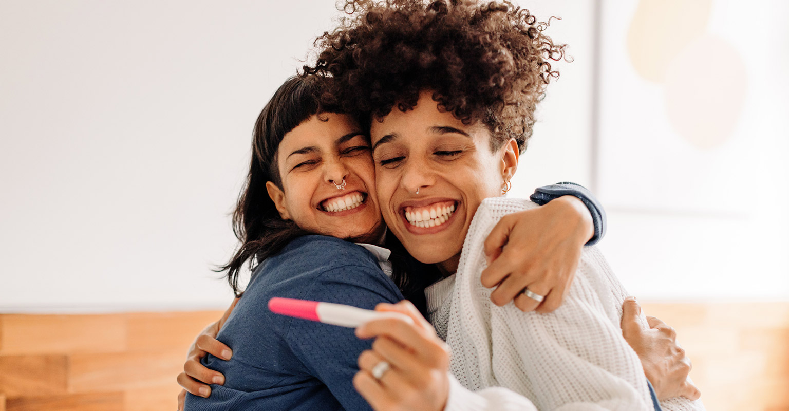 happy female couple viewing pregnancy test