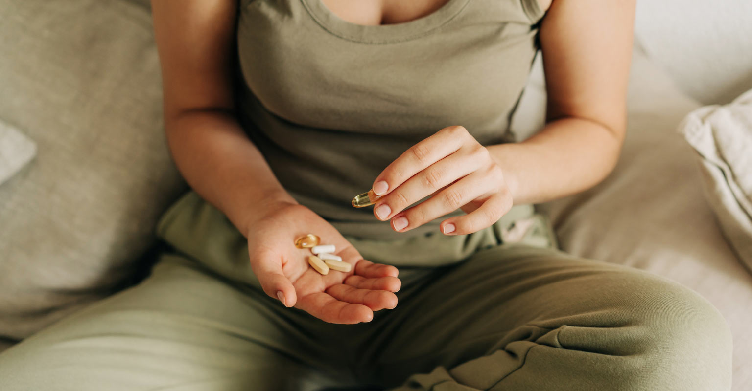 cropped photo of woman with supplements in hand