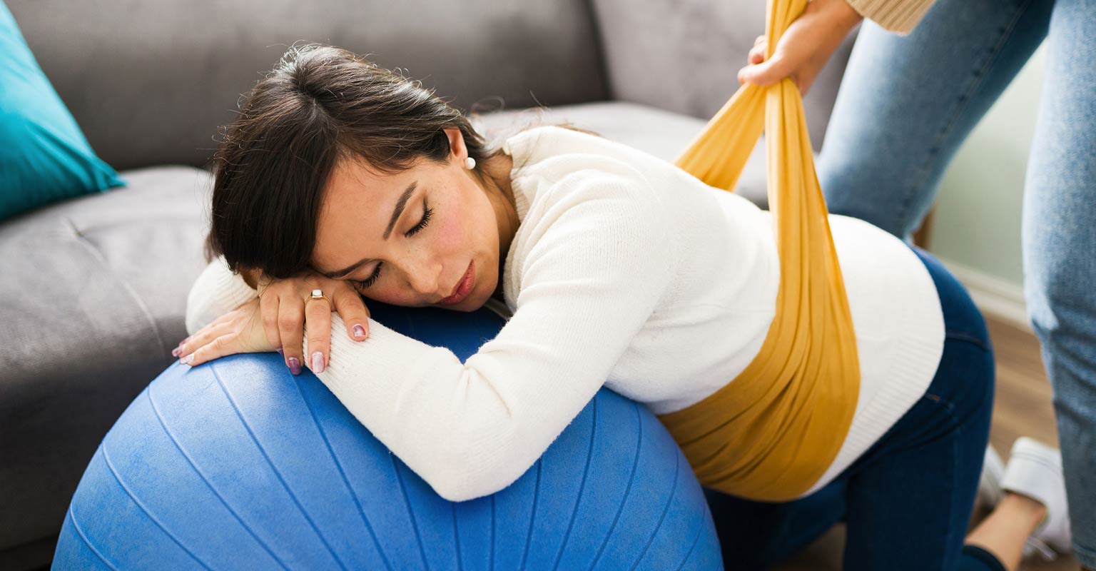 pregnant woman doing assisted prenatal stretches