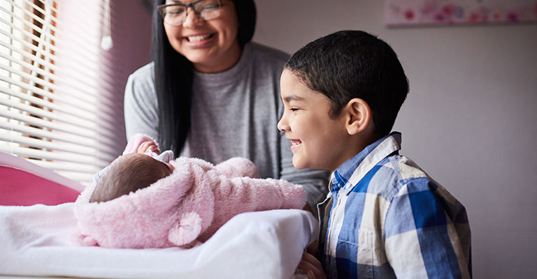 sibling smiling at newborn