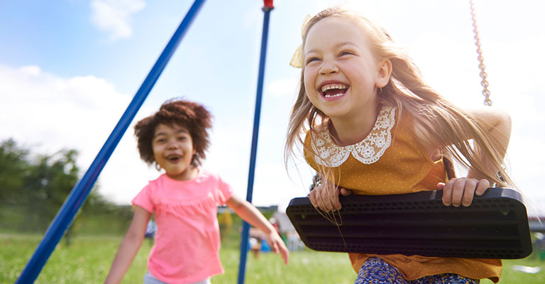 two young girls playing at the swings