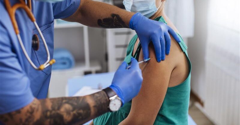 Healthcare distributing vaccine to patient