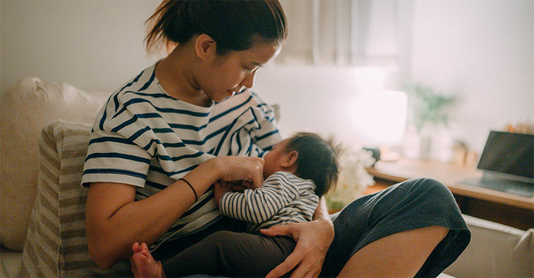 seated woman breastfeeding baby