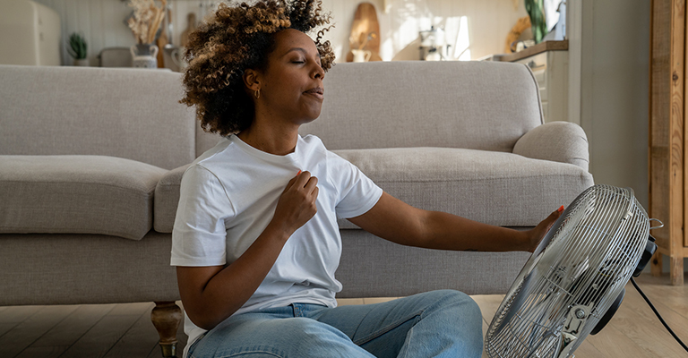a woman seated in front of a blowing fan