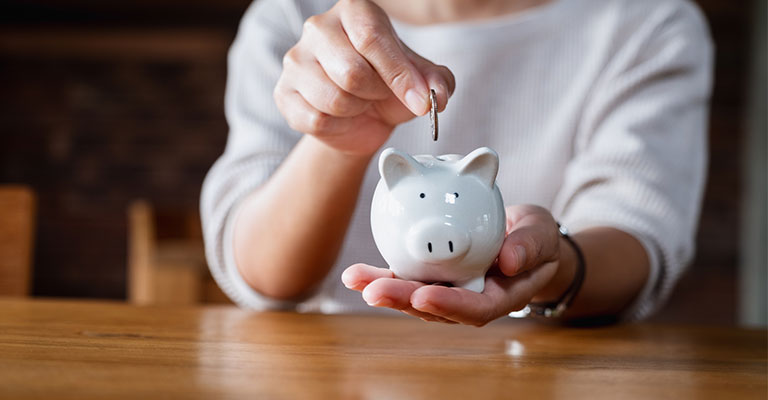 hand dropping a coin into a piggy bank