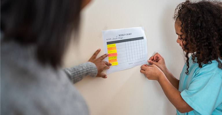 mother and child taping chart to a wall