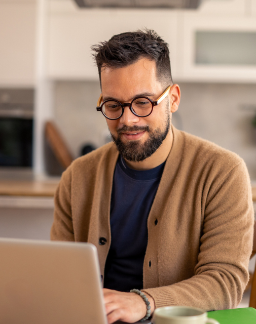 happy man in cardigan on computer