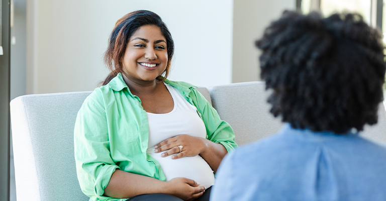 a happy pregnant woman seated on couch