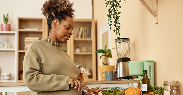 pregnant woman preparing healthy meal in the kitchen