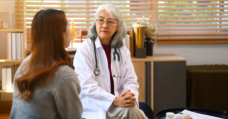 an older female doctor seated in consultation with patient