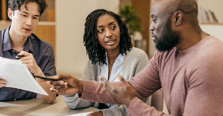 a couple discussing paperwork with an advisor