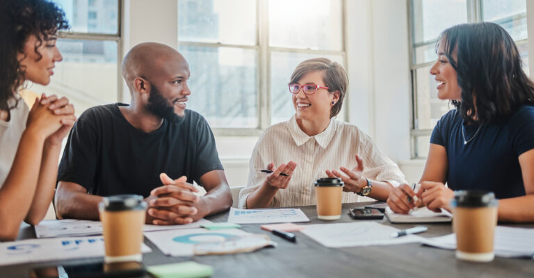 four colleagues seated together at a table, planning their future benefits