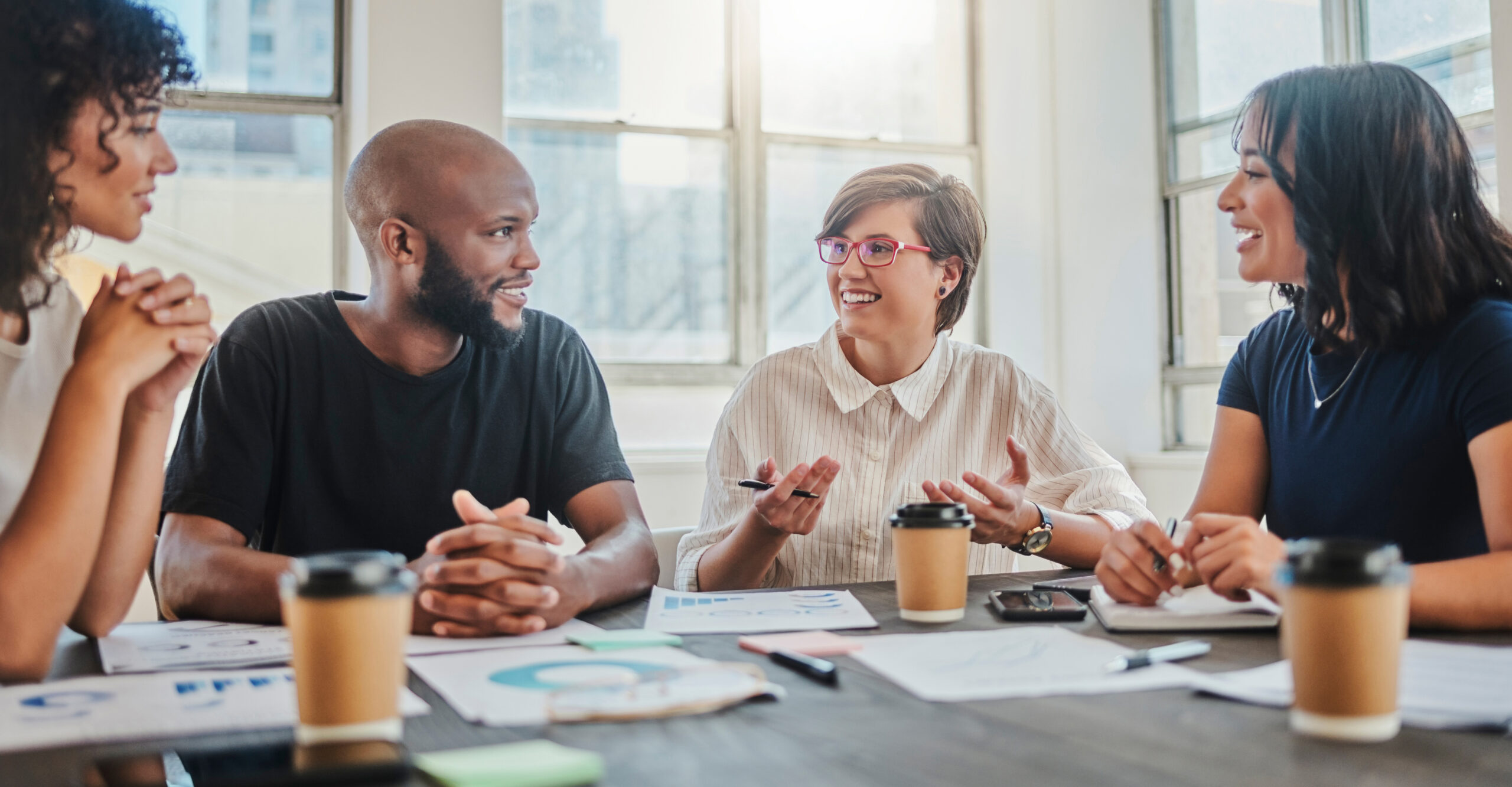 four colleagues seated together at a table, planning their future benefits