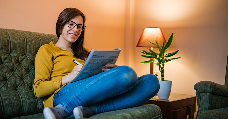 woman doing sudoku seated on the couch