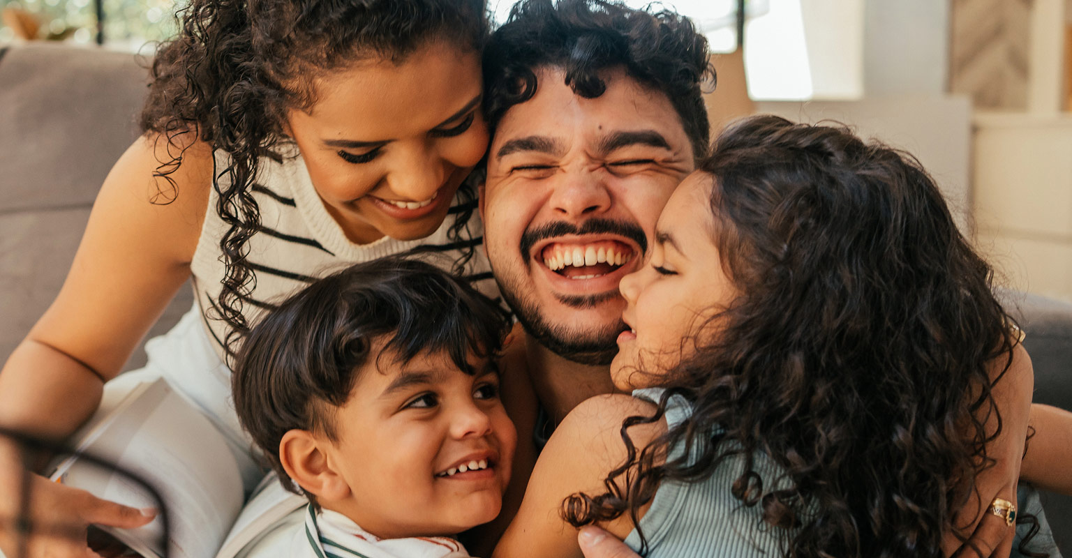 a hugging family of 4 smiling and laughing