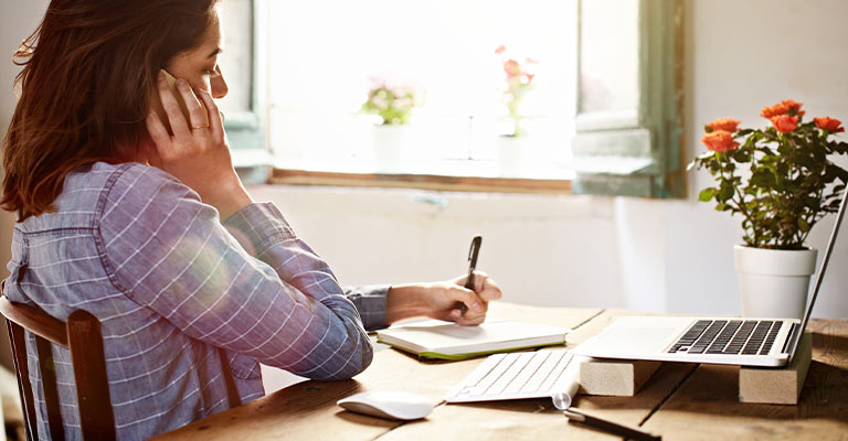 woman seated at table taking notes