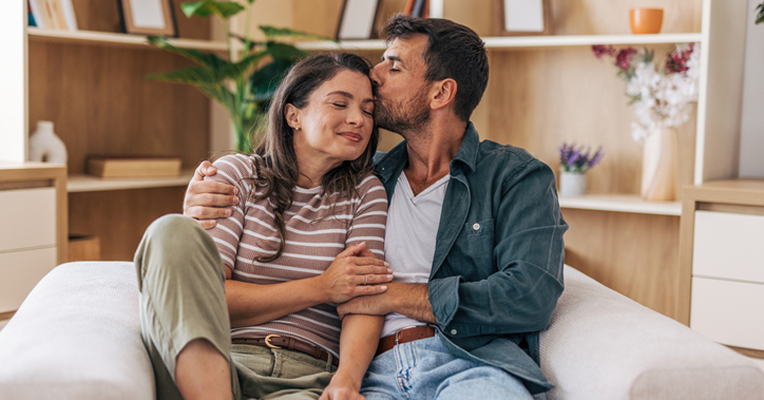 a seated couple embracing on the couch