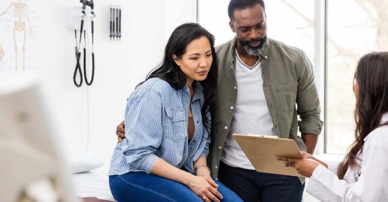 couple in exam room listening to their fertility provider