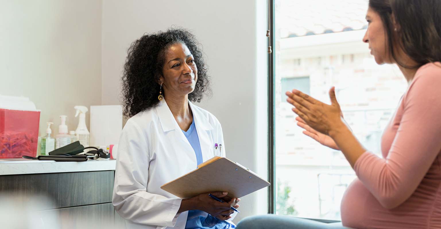 caring medical provider listening to pregnant patient