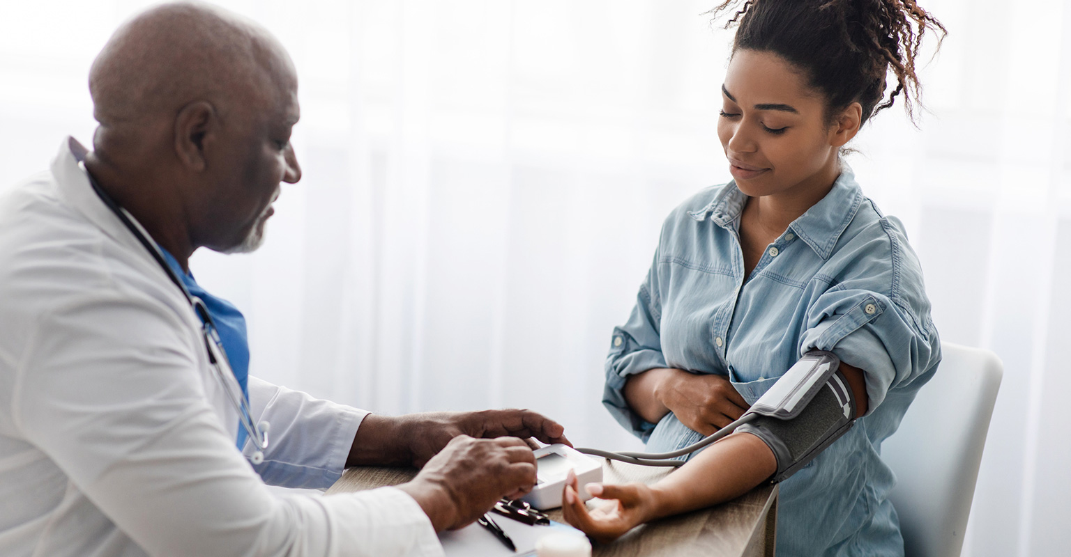woman with her medical provider checking her blood pressure