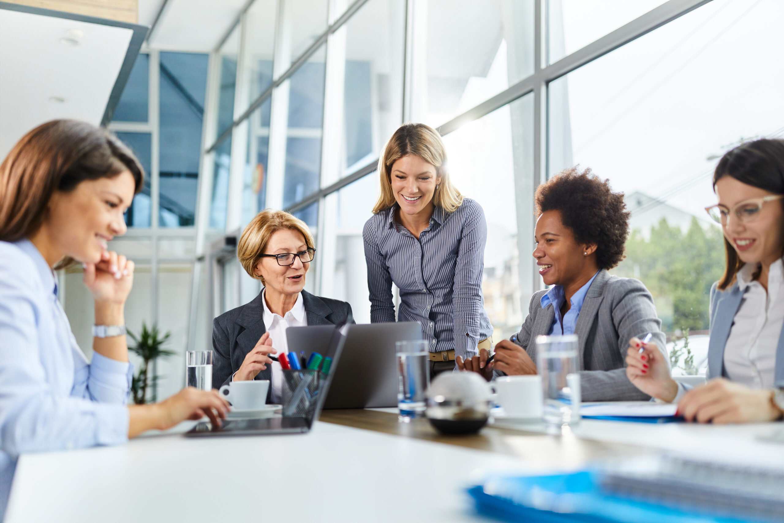 Group of happy female entrepreneurs cooperating while working on a computer during a meeting in the office.