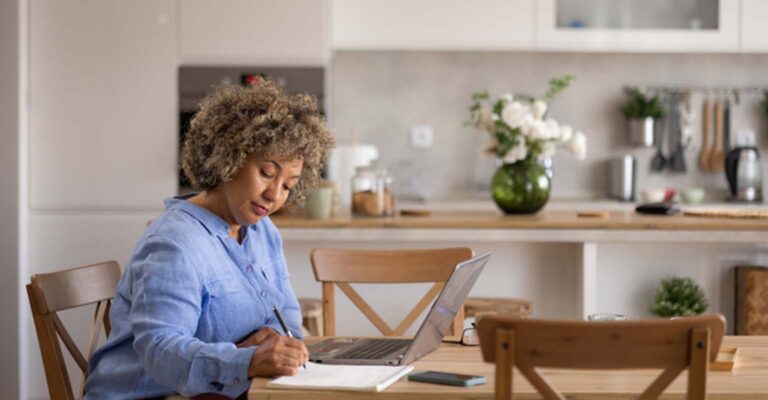 older woman taking notes on her dining room table